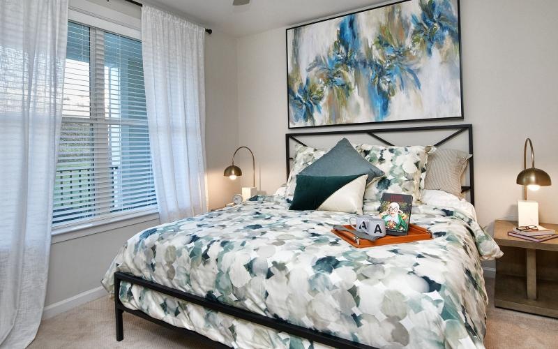 Model bedroom at Rosalia Verdae senior living apartments in Greenville, SC, featuring carpeted flooring.